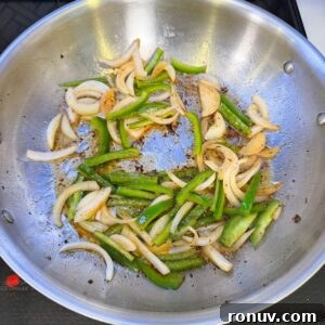 Southern Fried Cabbage Recipe with Bacon and Onions 5 Onions and peppers cooking in a pan.