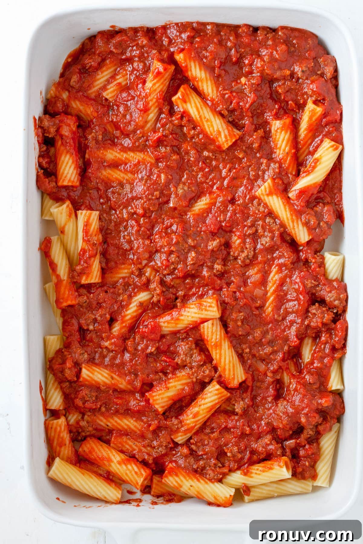 Baked Rigatoni with Cheese and Tomato Sauce 7 Rigatoni al Forno assembling in a baking dish.