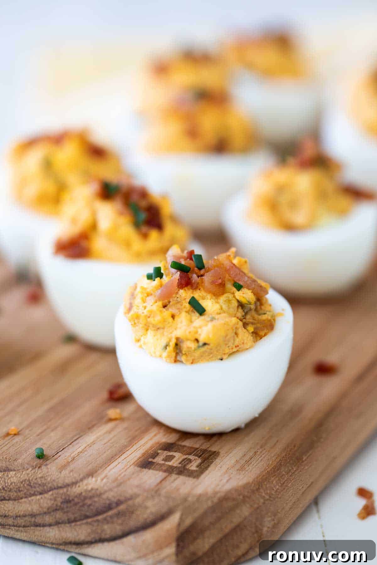 What could be better than bacon and eggs? These Deviled Eggs with Bacon add salty bacon to a traditional deviled egg recipe for an appetizer that will disappear off the plate. Bacon Deviled Eggs topped with pieces of bacon and chives.