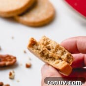 Classic Pecan Sandies Recipe 9 Pecan sandies cookies broken in half and hand held.