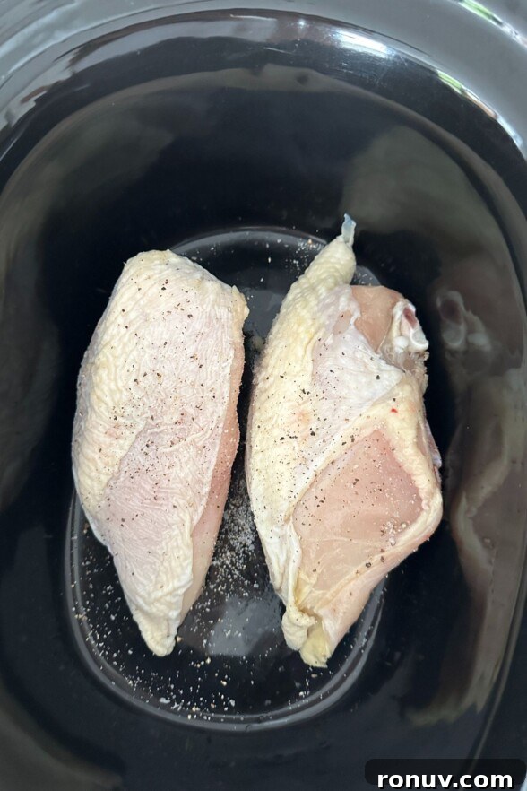 Vietnamese Chicken Salad with Tangy Nuoc Cham Dressing 3 Seasoned raw chicken breasts laying in a black crock pot ready to cook.