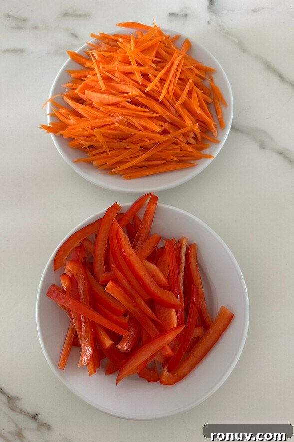 Vietnamese Chicken Salad with Tangy Nuoc Cham Dressing 4 Shredded carrots and sliced red bell peppers in two small white bowls, set against a clean white background.