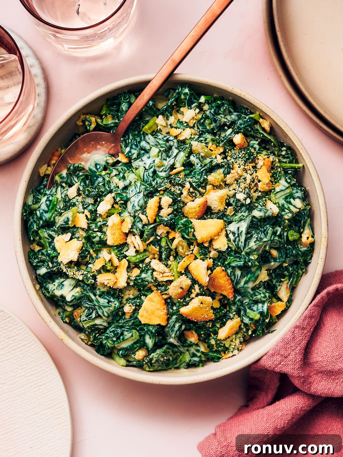 Creamed Kale Recipe: Garlic and Parmesan Side Dish 2 Easy vegetarian Creamed Kale in a serving bowl with a spoon on a dining table.