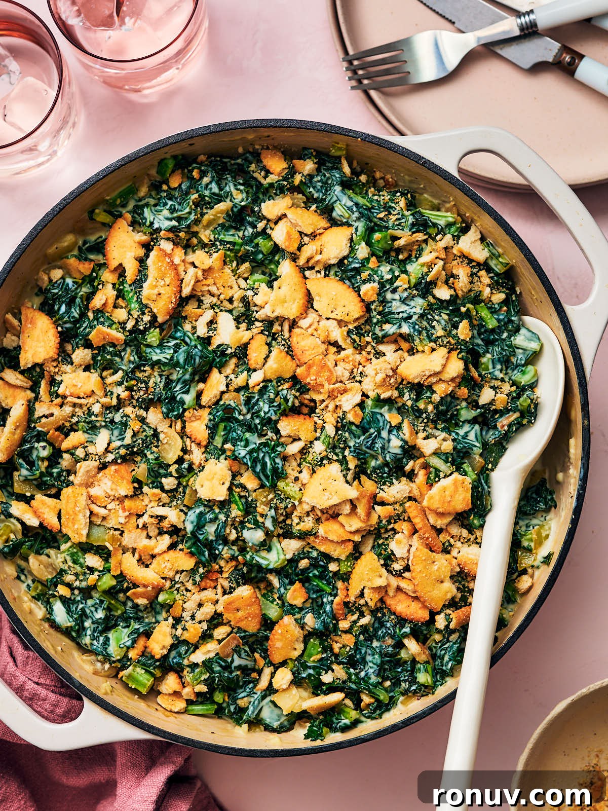 Creamed Kale Recipe: Garlic and Parmesan Side Dish 14 Easy Creamed Kale in a skillet with a serving spoon on a dining table.