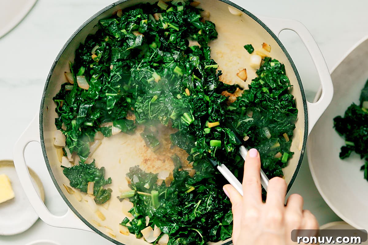 Creamed Kale Recipe: Garlic and Parmesan Side Dish 9 Removing cooked kale from a pan with kitchen tongs.