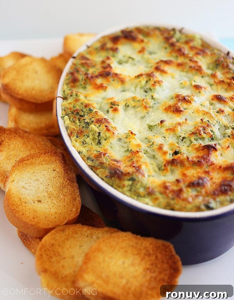 Baked hot cheesy spinach-artichoke dip served with toasted baguette slices