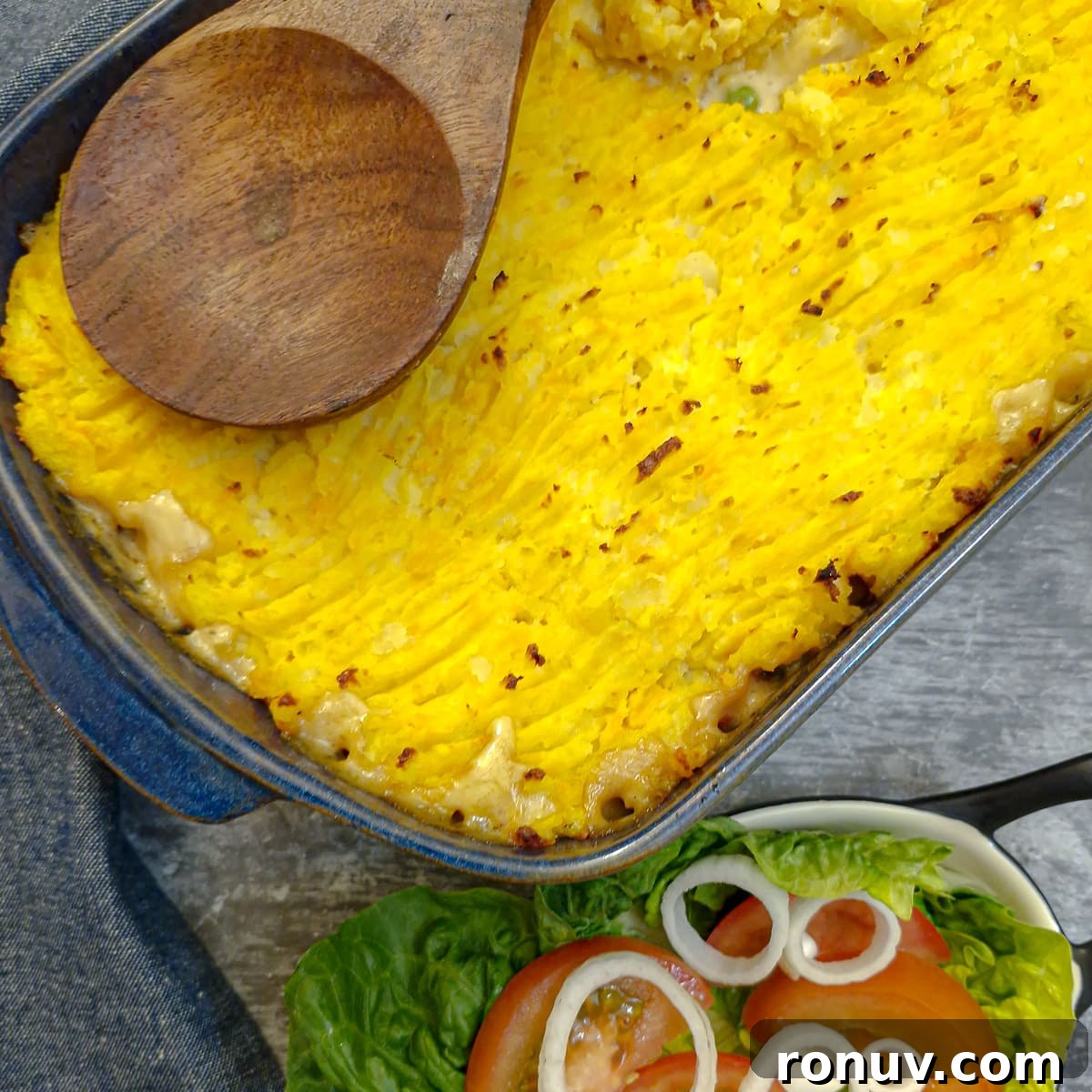 Turn Leftover Chicken Into Shepherd's Pie 2 A dish of leftover shepherd's pie topped with potato and sweet potato mash, with a dish of green salad in the foreground.