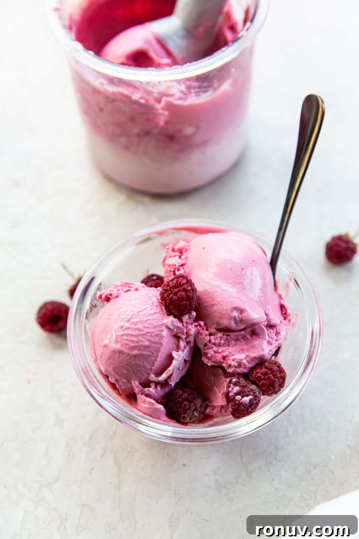 No-Churn Raspberry Cheesecake Ice Cream Recipe 2 Raspberry ice cream in a bowl with raspberries.