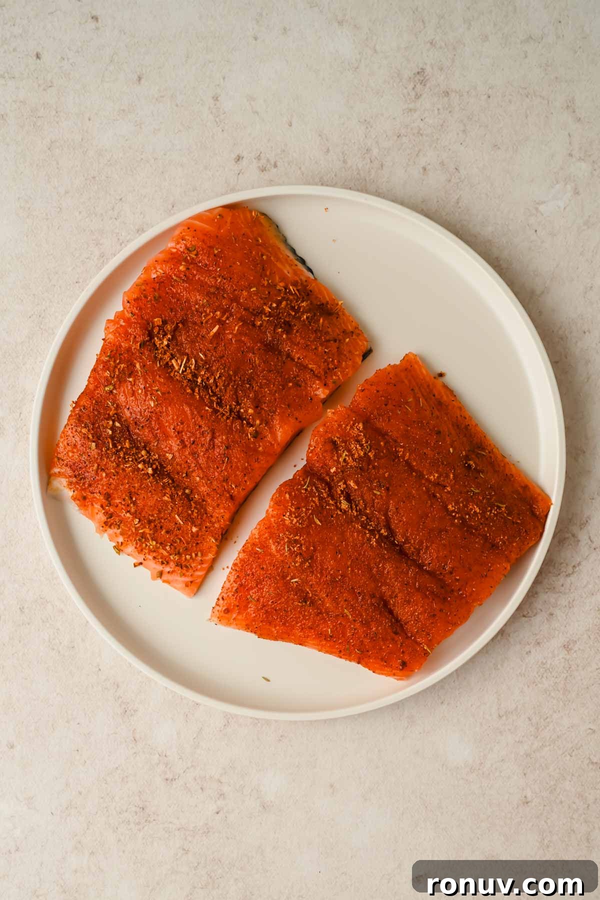 Salmon BLT Sandwich Recipe with Avocado & Lemon-Dill Mayo 6 two raw pieces of salmon with blackening seasoning on white plate.