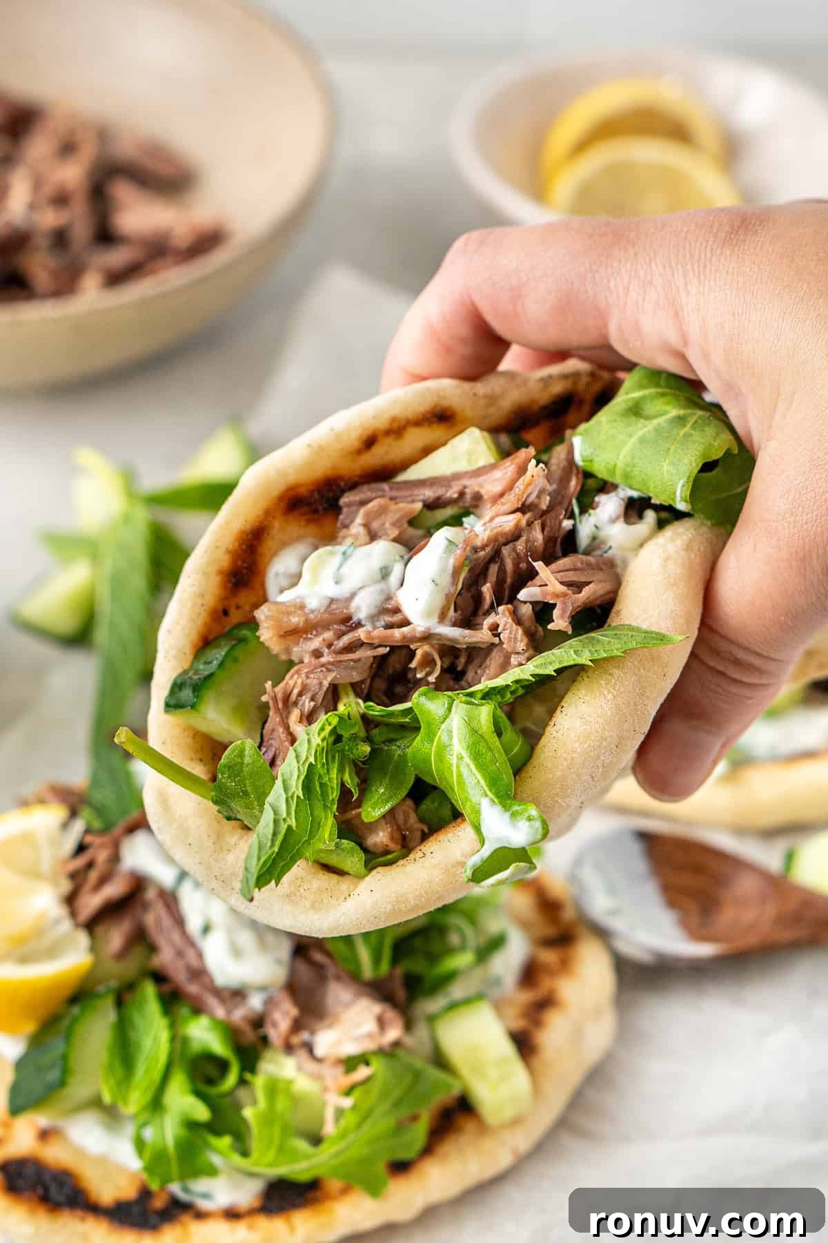 Grilled Greek Lamb Pitas with Tzatziki and Feta 13 A hand picking up a lamb pita.