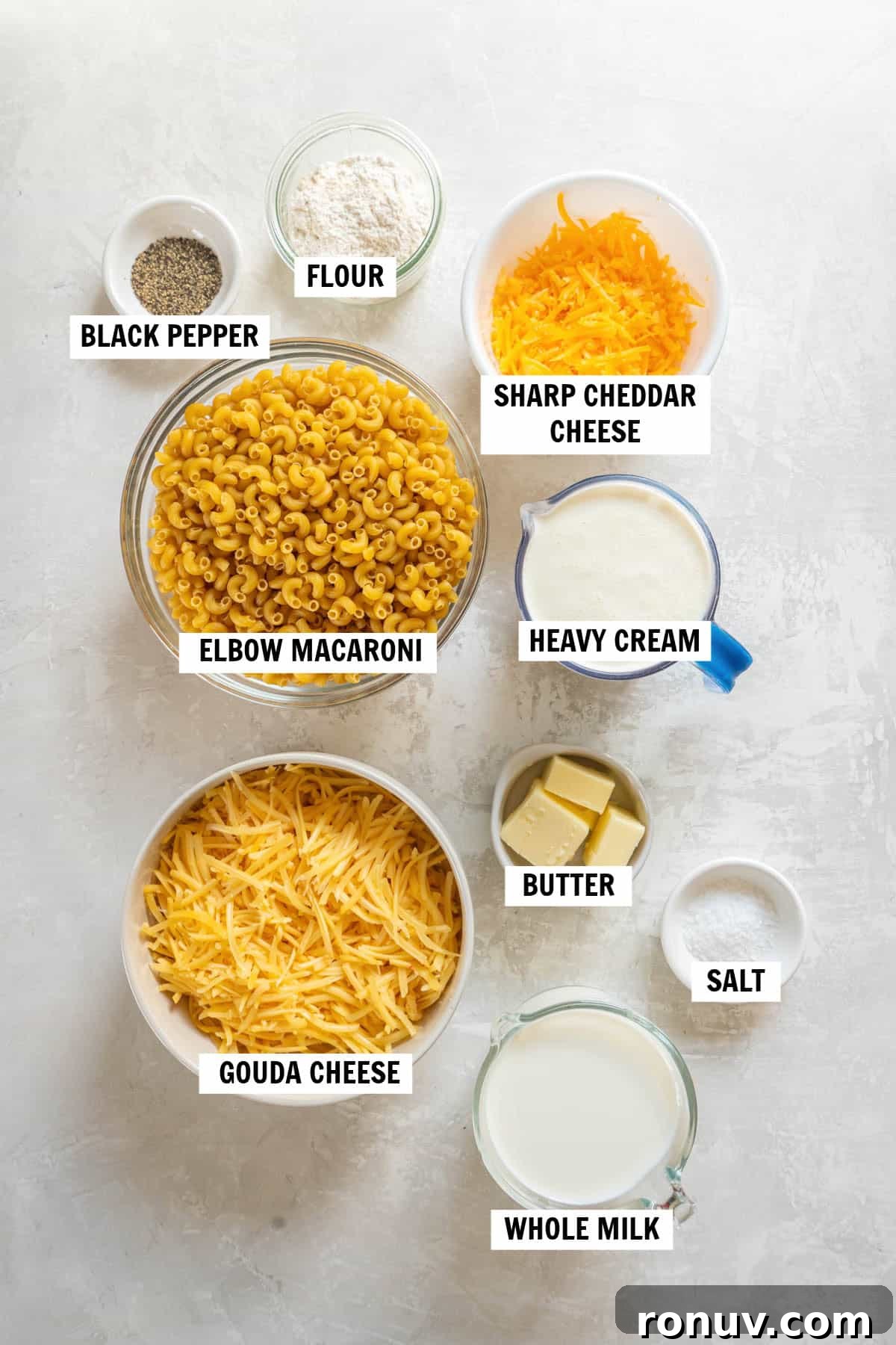 All of the ingredients for gouda mac and cheese in bowls on a white countertop. 
