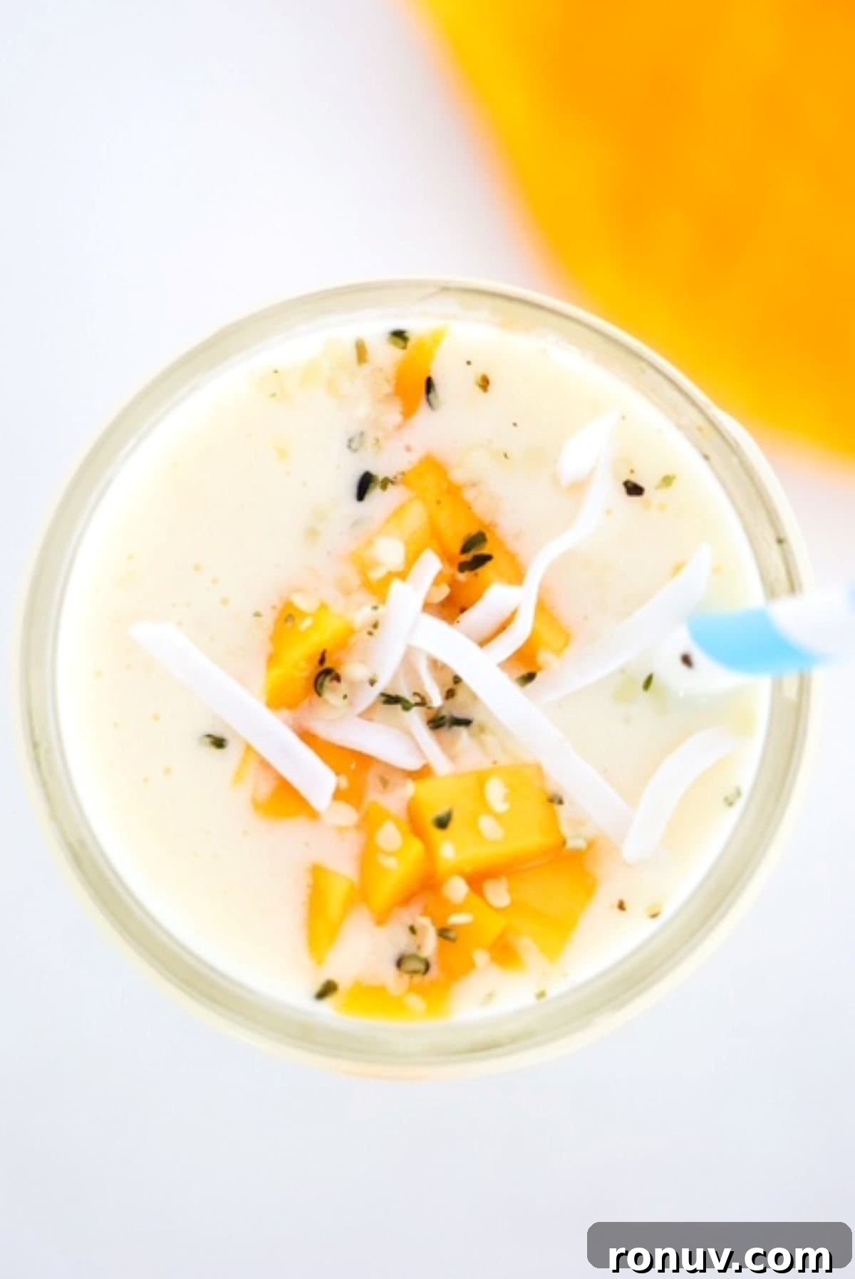 Tropical Mango Pineapple Smoothie Recipe 2 Mango Pineapple Smoothie topped with mango pieces and coconut flakes.