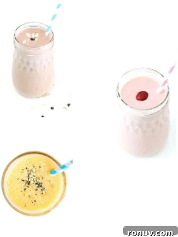Three different smoothies in glass jars with striped straws.