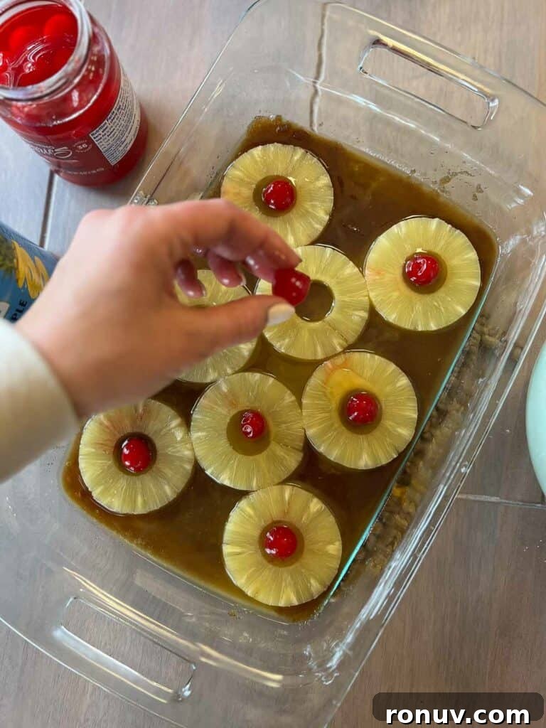 Gluten-Free Pineapple Upside-Down Cake Recipe 6 Gluten free pineapple upside down cake being made by pineapple rings and cherries being added to pan