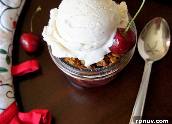 Sweet Cherry Crisp in Mason Jar Sweet Cherry Crisp in a small mason jar topped with a scoop of vanilla ice-cream and a cherry