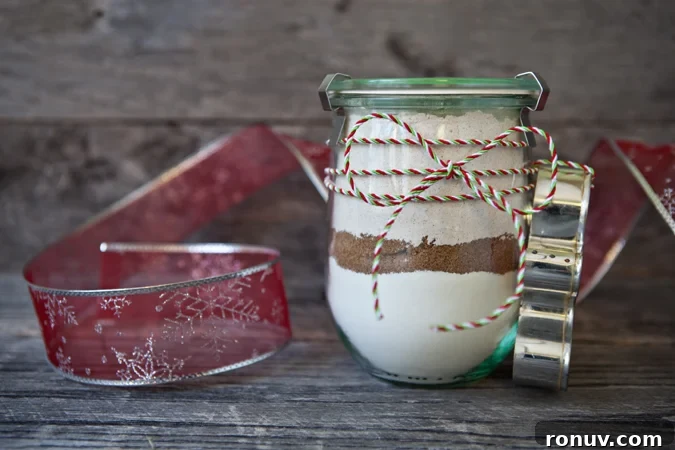 gingerbread-cookie-mix-in-a-jar-slider Gingerbread Cookie Mix in a a Jar displayed on a table next to some ribbon and a cookie cutter.