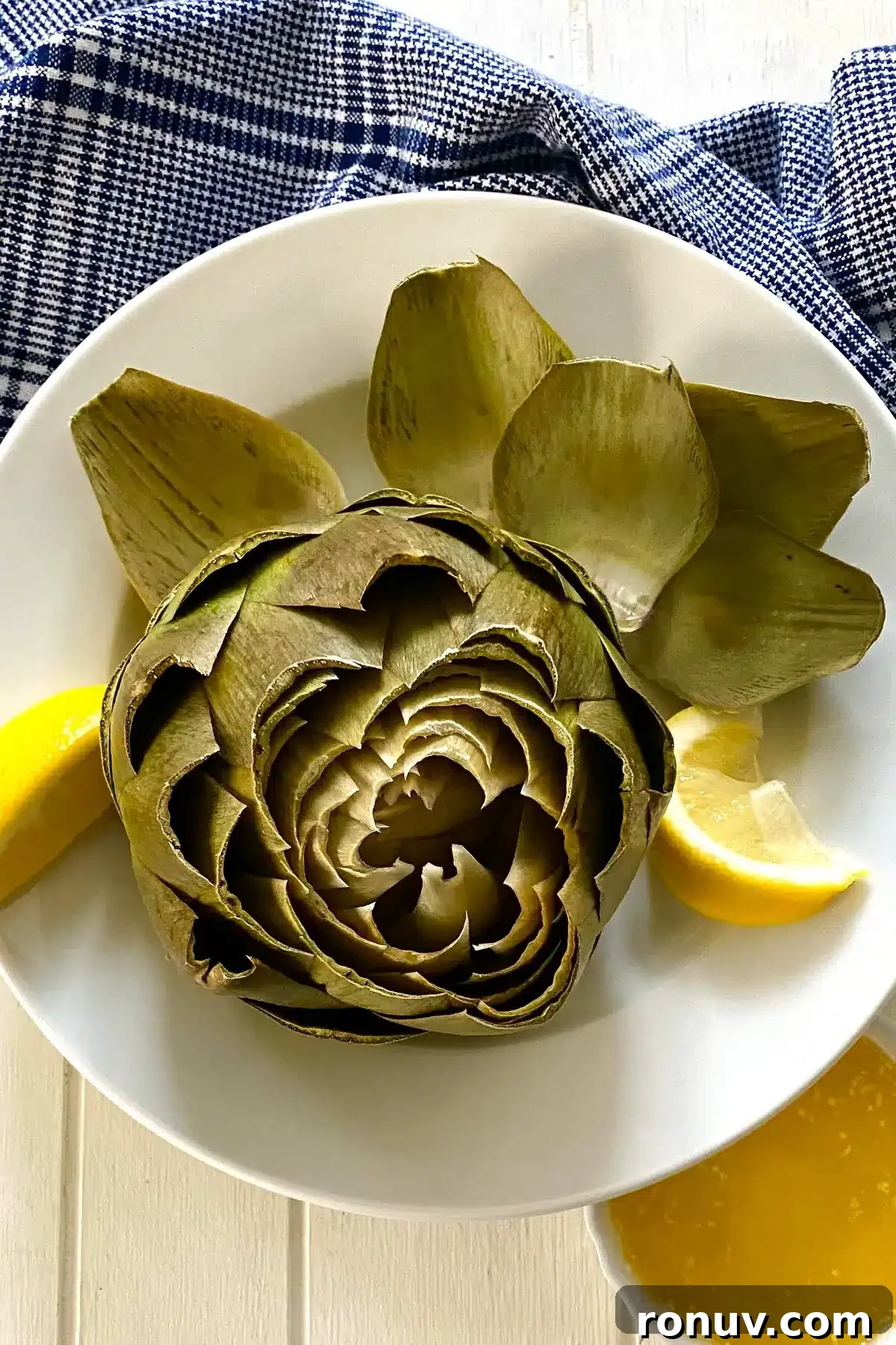 How to Cook Artichokes in the Microwave 3 a cooked artichoke with lemon and some leaves removed.