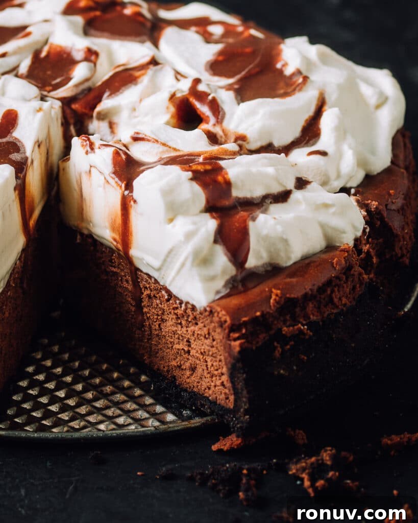Valentine's Day Dessert Recipes for Date Night 7 Chocolate cheesecake with whipped cream and chocolate drizzle with a slice cut.