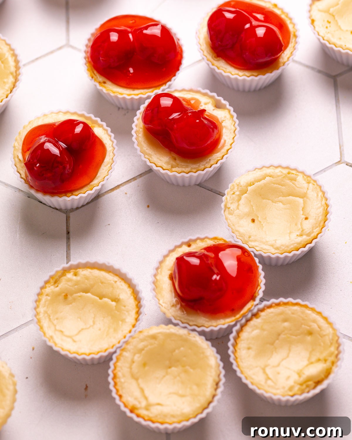 Valentine's Day Dessert Recipes for Date Night 10 Mini cheesecake bites in liners, some topped with cherry filling.