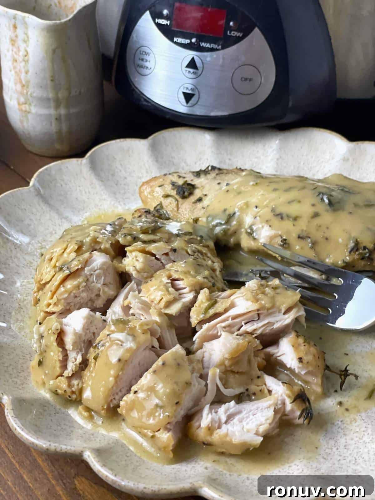 Slow-Cooker Turkey Tenderloins in Honey Mustard Gravy 7 A cut up turkey tenderloin covered in gravy on a scalloped plate in from of a crockpot.
