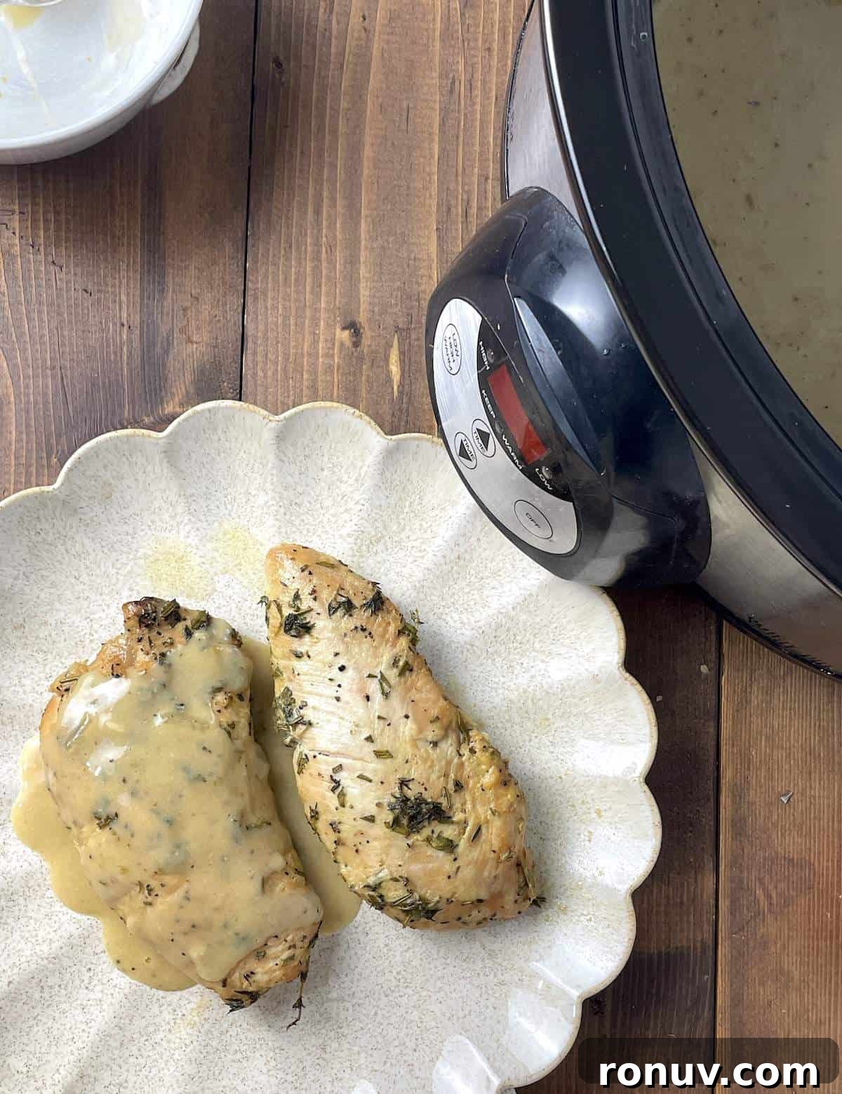 Slow-Cooker Turkey Tenderloins in Honey Mustard Gravy 8 Two cooked turkey tenderloins with gravy on a scalloped plate next to a crockpot.