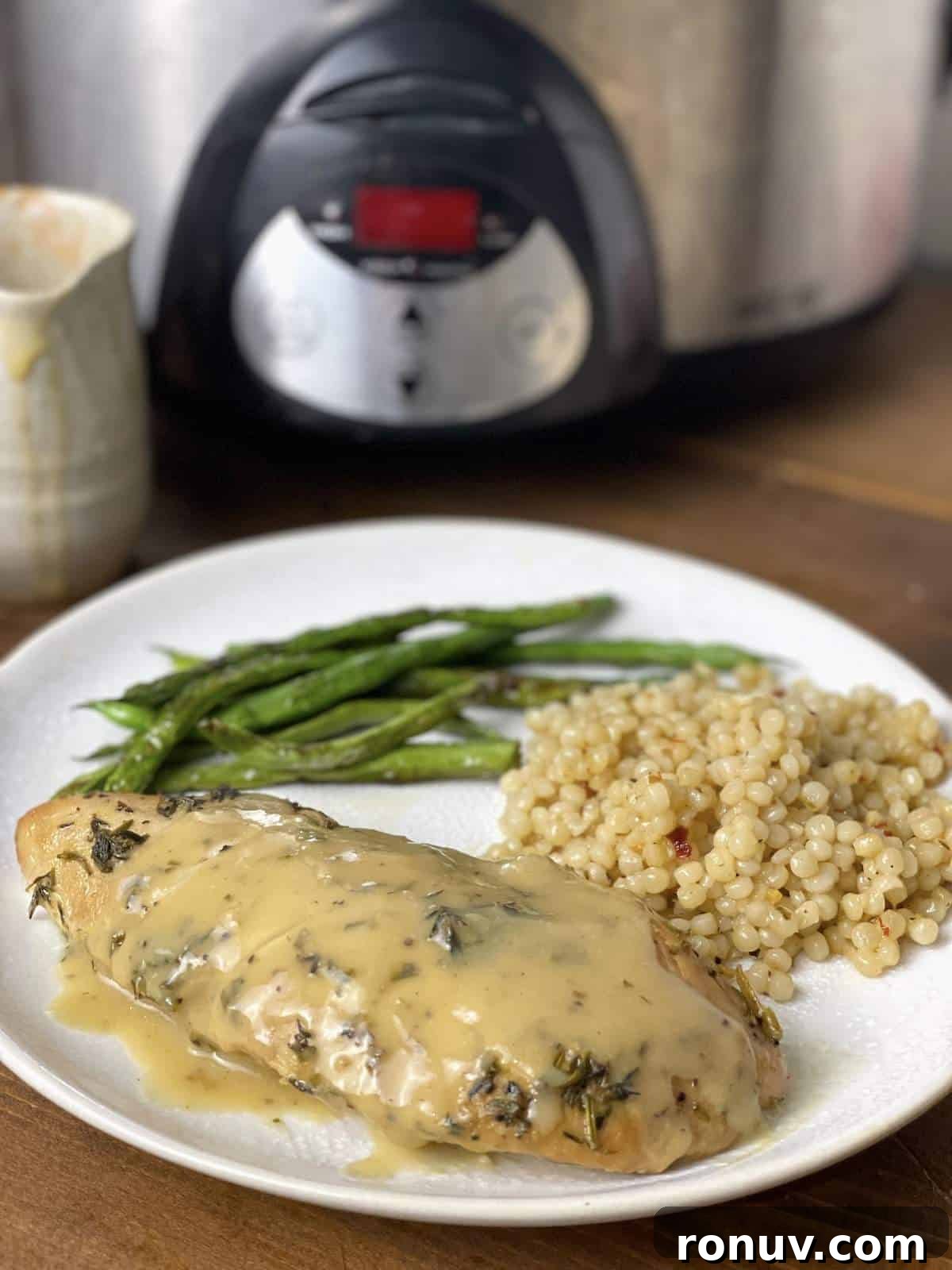Slow-Cooker Turkey Tenderloins in Honey Mustard Gravy 9 A cooked turkey tenderloin with Israeli couscous and green beans on a plate in front of a crockpot.