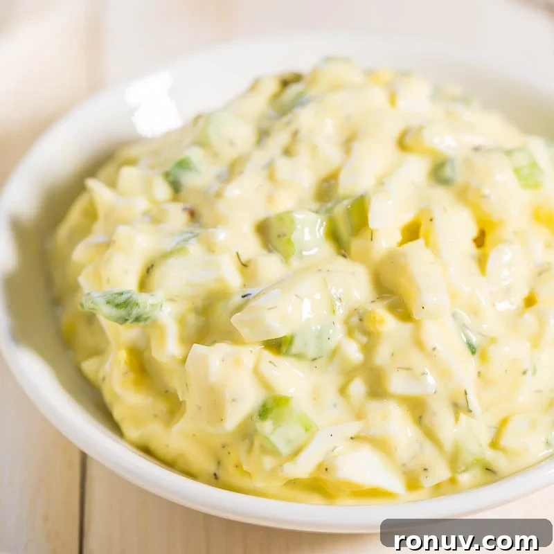 A bowl of creamy potato salad with chopped green herbs.