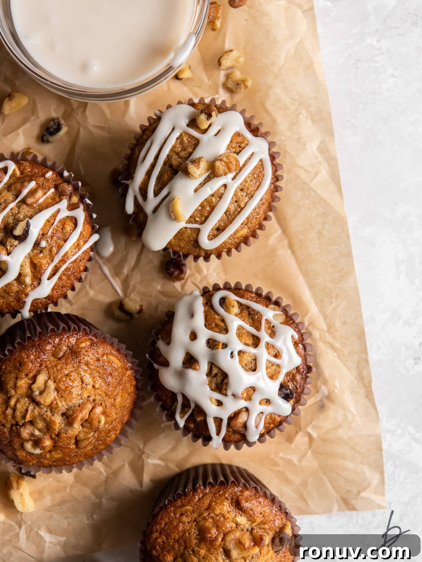 Maple Walnut Muffins Recipe 2 parchment paper with a few maple muffins with glaze and walnut on top.