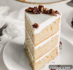 white round plate with slice of triple layer maple cake with cream cheese frosting and candied pecans