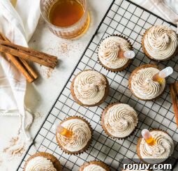buttered rum cupcakes topped with frosting, cinnamon and rum on wire cooling rack