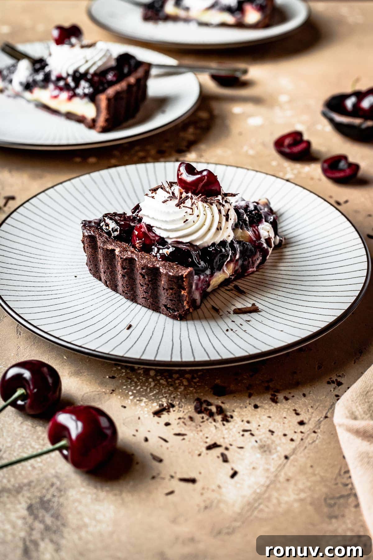 Decadent Chocolate Cherry Tart Recipe 3 A slice of fruit tart with a swirl of whipped cream and cherries on top.