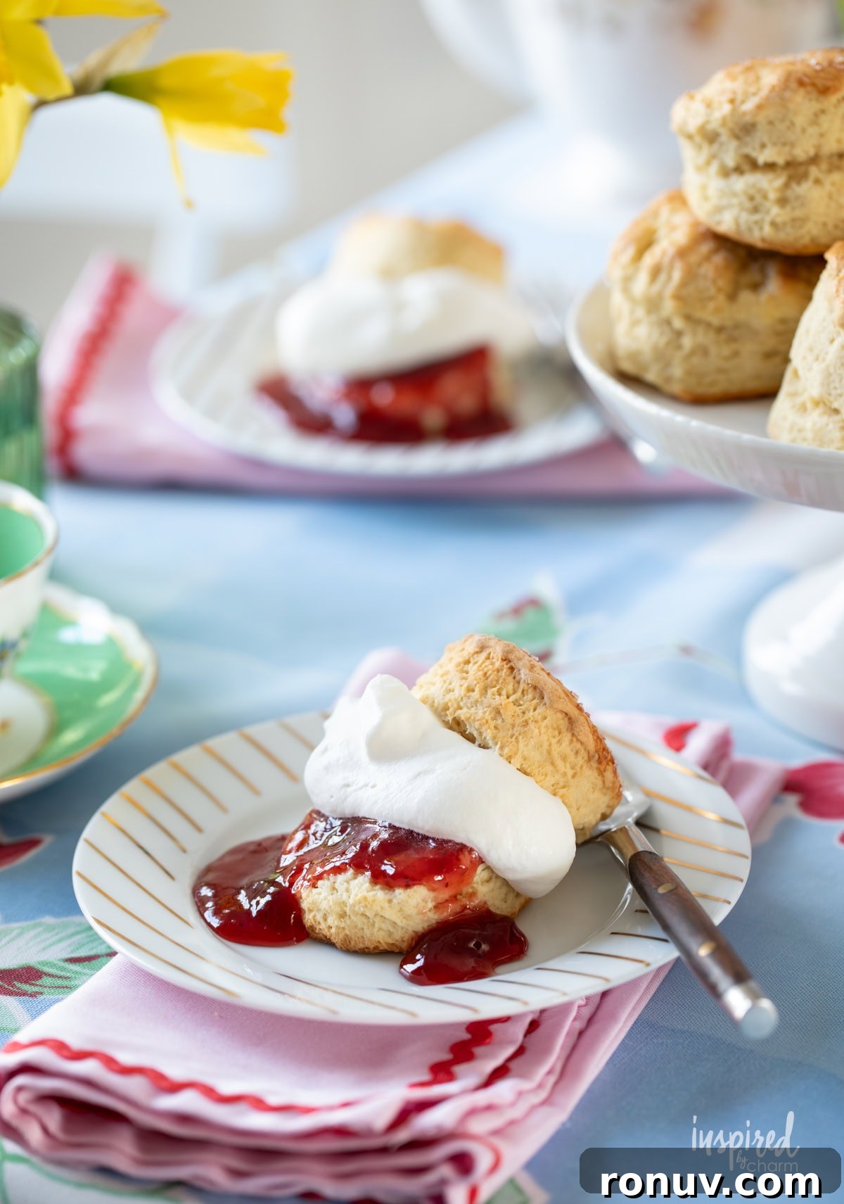 Classic Buttery Homemade Scones Recipe 16 two scones served with whipped cream and strawberry jam on small plates.