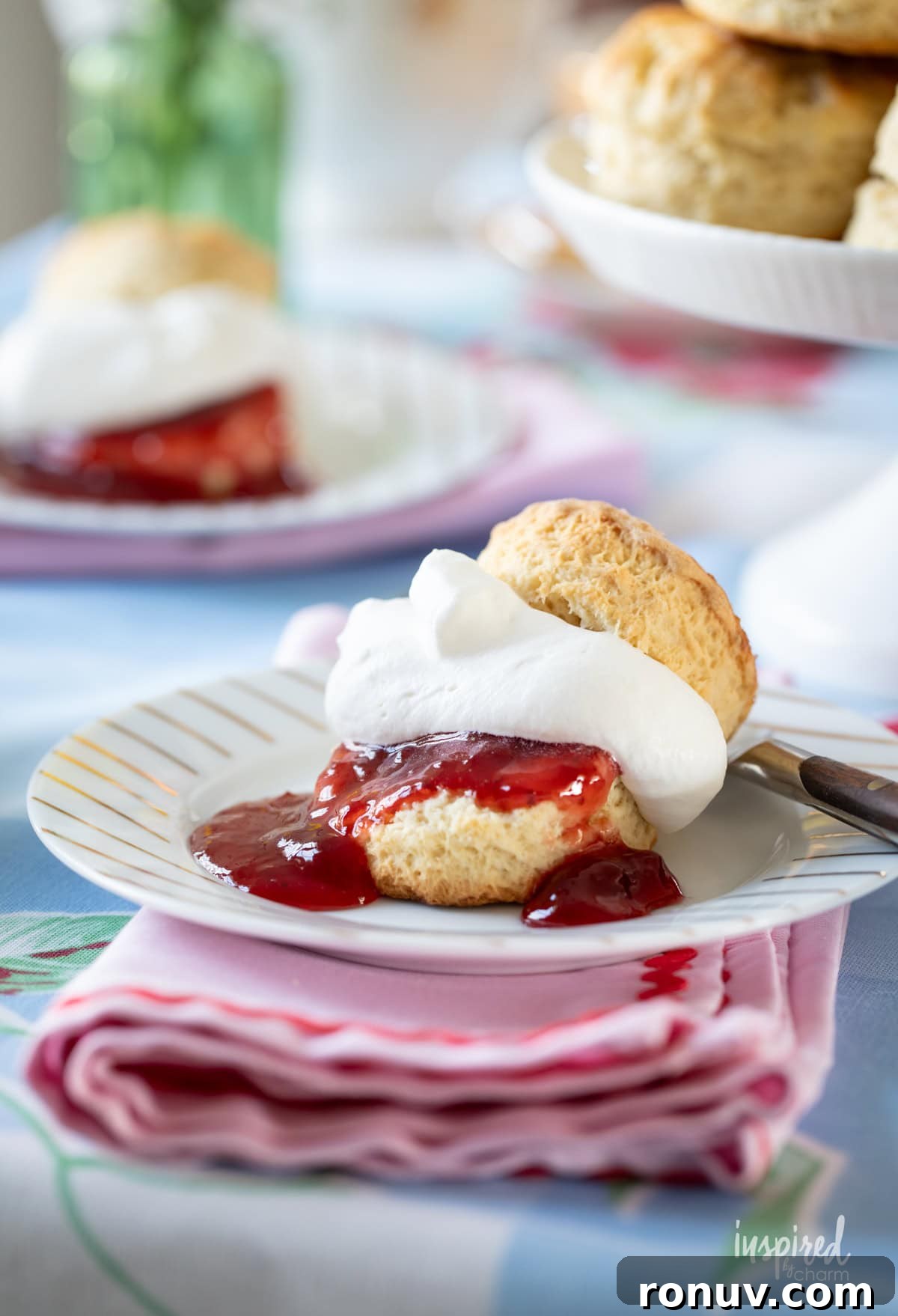 Classic Buttery Homemade Scones Recipe 5 scone served with whipped cream and strawberry jam on a plate with a fork.
