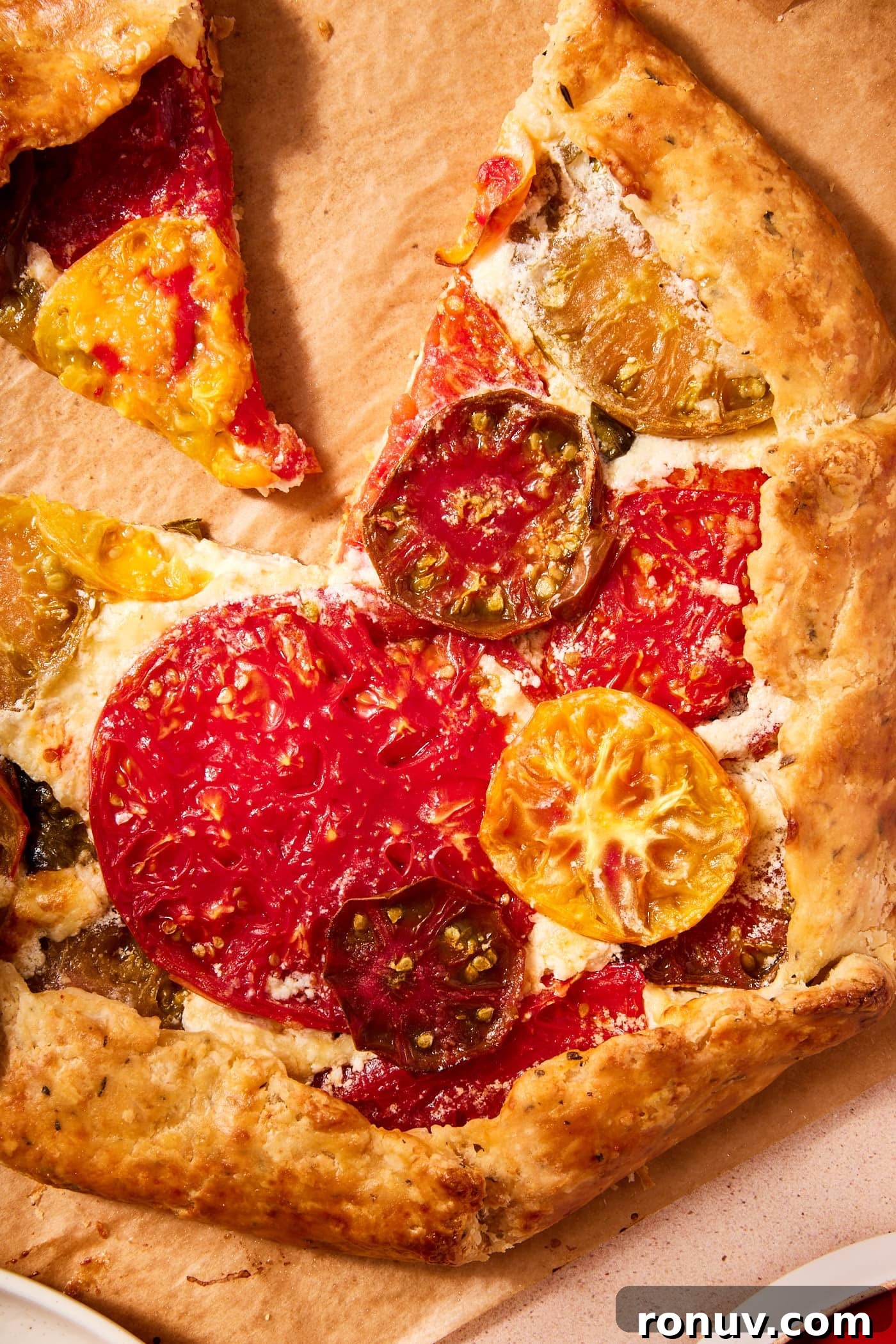Fresh Tomato Galette Recipe with Basil 17 Baked tomato galette with golden brown crisped tomatoes with crispy crust all on piece of parchment.