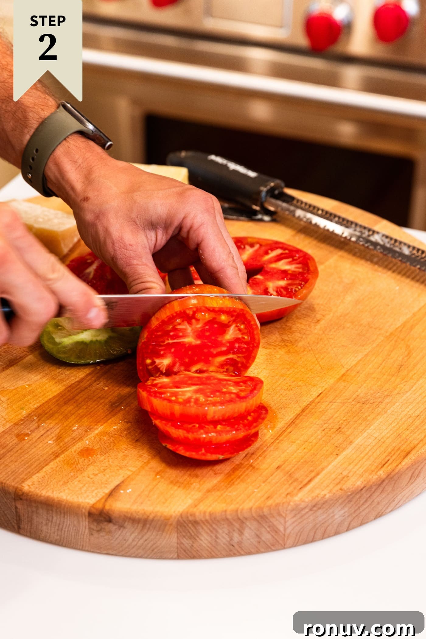 Fresh Tomato Galette Recipe with Basil 7 Knife slicing tomato into slices on wood cutting board with more tomatoes in background.