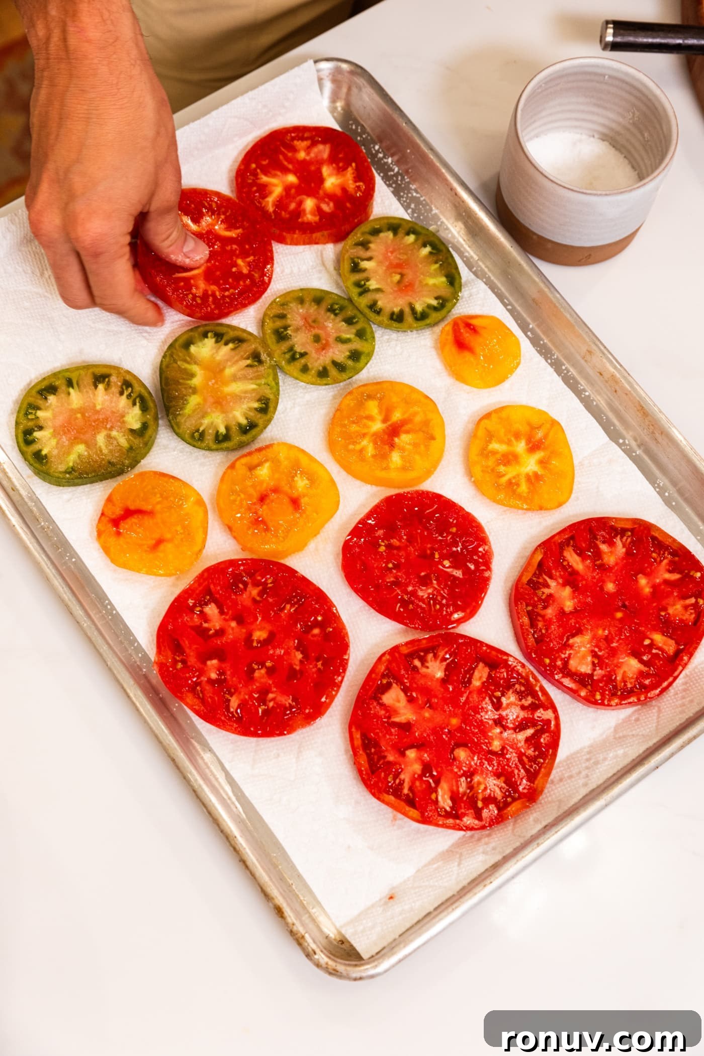 Fresh Tomato Galette Recipe with Basil 8 Slices of tomato sitting on pieces of paper towel on a baking sheet.