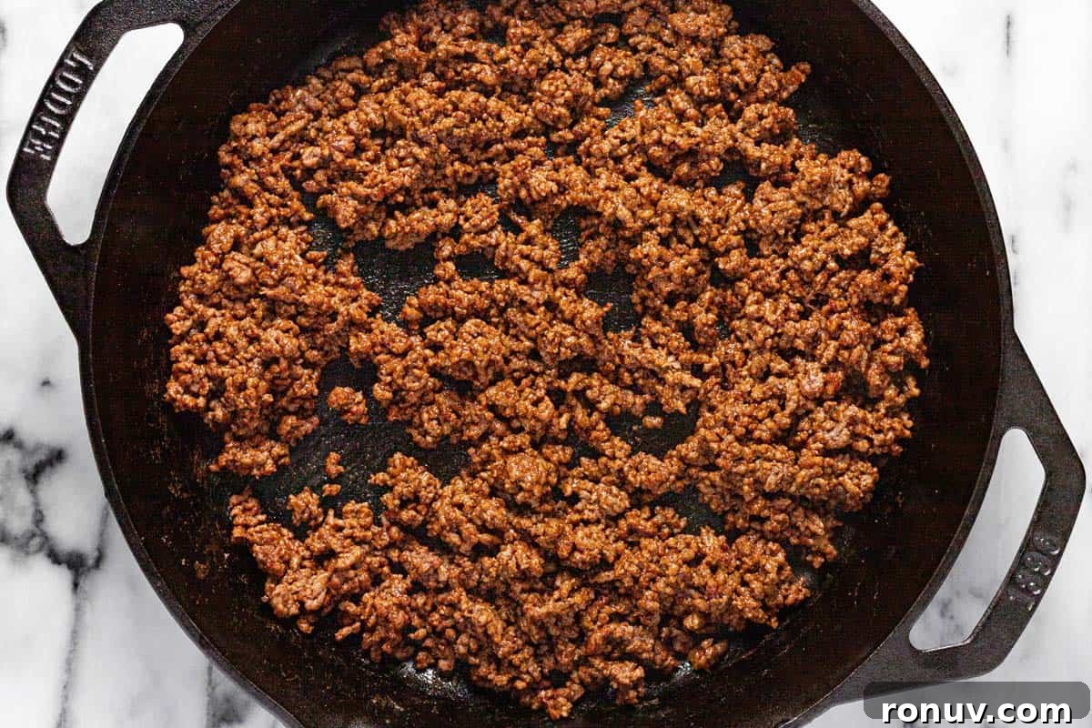 Creamy Cheesy Rotel Dip Recipe 4 Cast iron skillet filled with browned ground beef seasoned with taco seasoning.