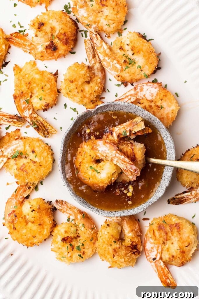 Crispy Baked Coconut Shrimp with Apricot-Chili Dip 8 Gluten free coconut shrimp shown being dipped in a chili apricot dipping sauce.