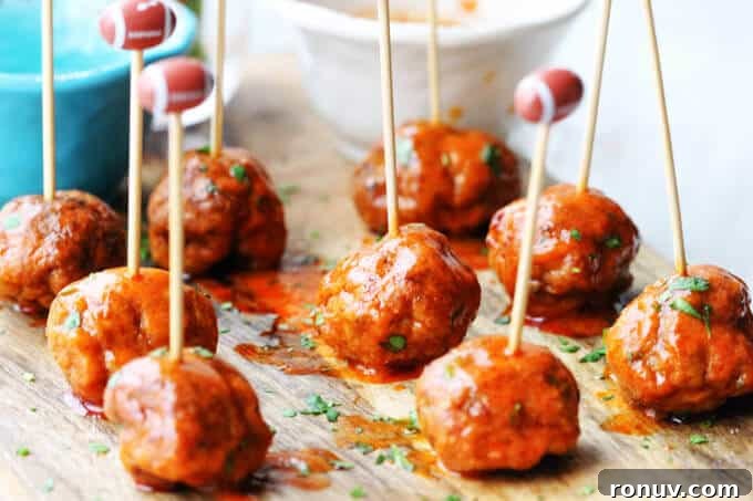 Buffalo Turkey Meatballs are a perfect appetizer for the Big Game. They're also a lighter alternative to a traditional chicken buffalo wings, not only because they have less fat, but also because they're baked, not fried. Not to mention they're also super easy to make. Buffalo Turkey Meatballs with football sticks and bowls with sauces in the back, vertical