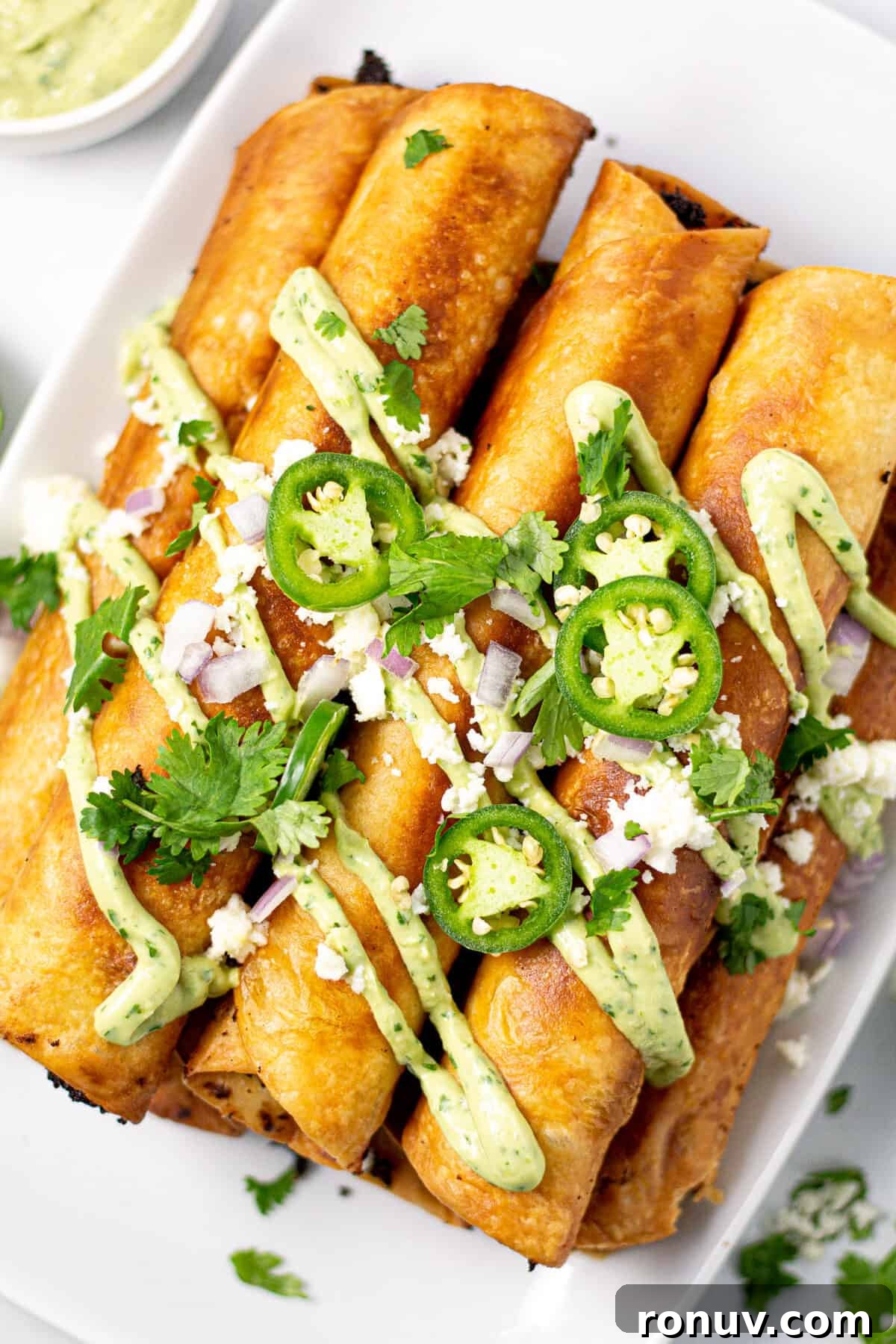 Overhead shot of a platter filled with flautas garnished with cilantro