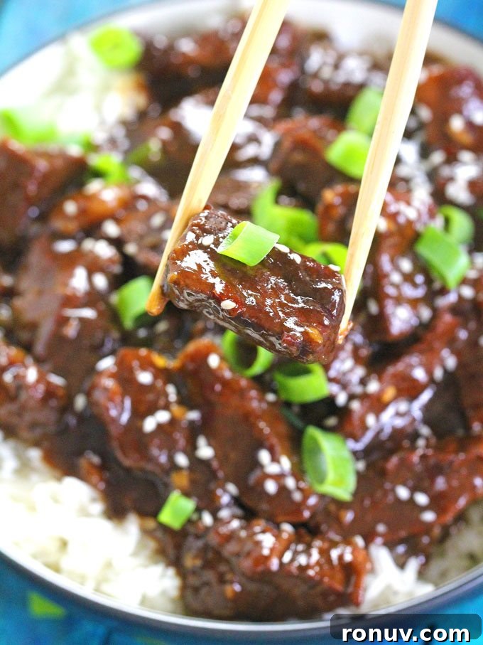chopsticks holding a piece of Mongolian Beef