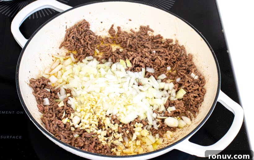 Slow Cooker Lasagna Recipe: Tender, Cheesy Comfort 3 Ground beef, onion, and garlic in a large white skillet.