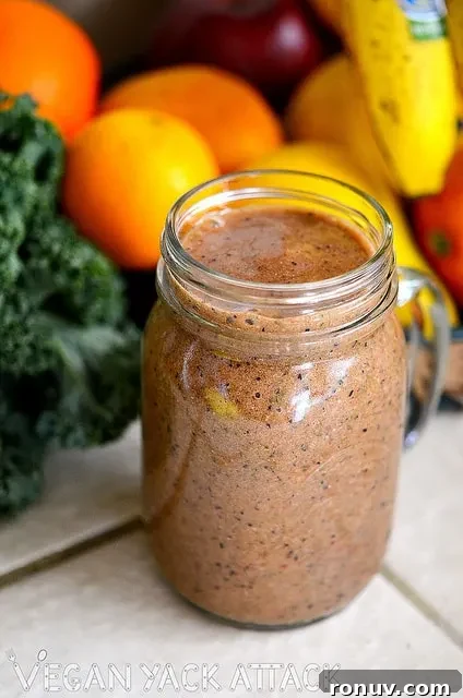 Speckled Strawberry Smoothie in a glass jar in front of fresh fruit and kale