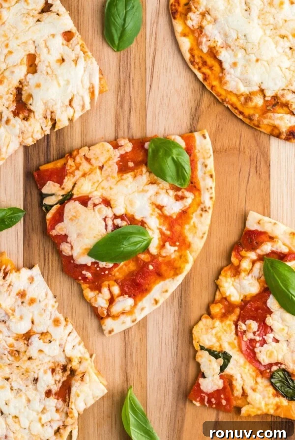 Tortillas covered with melted cheese and pizza toppings on a wooden cutting board.