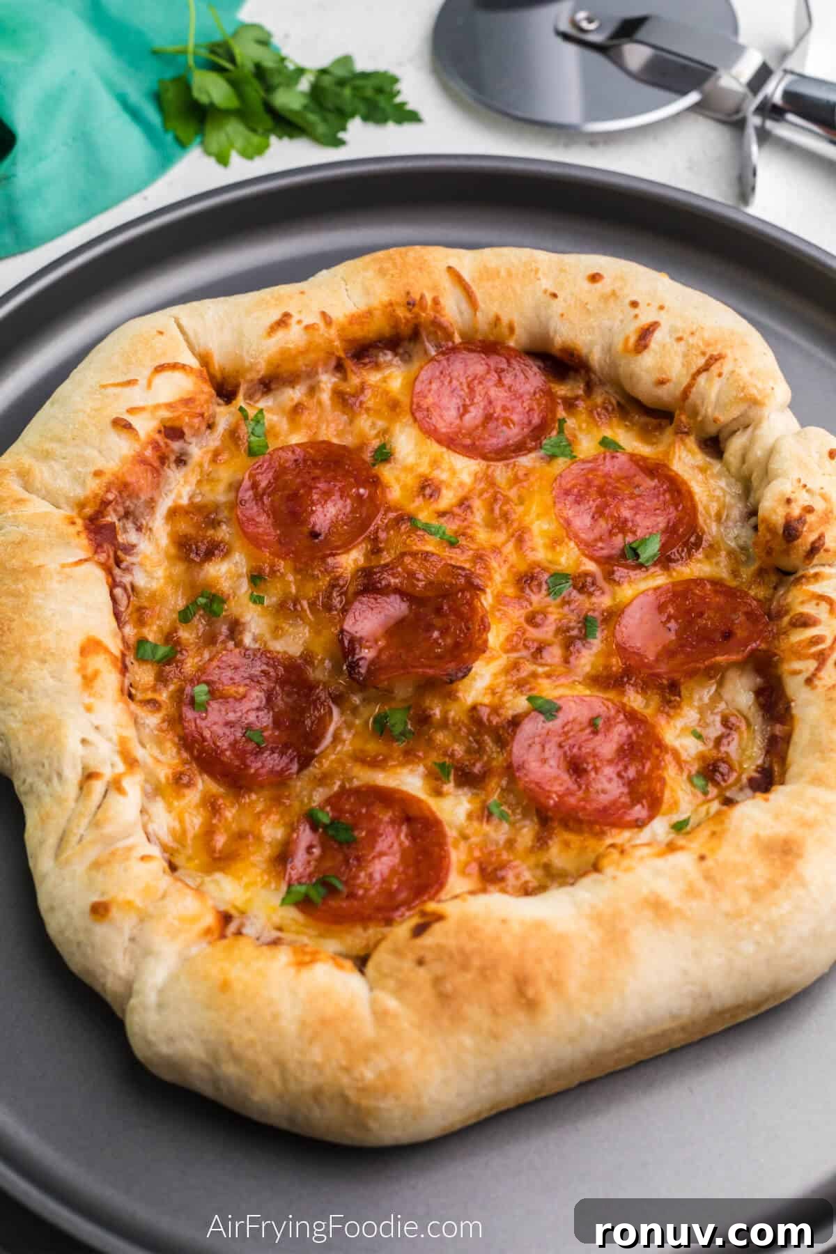 Air fryer pizza on a serving plate ready to be cut and served. 