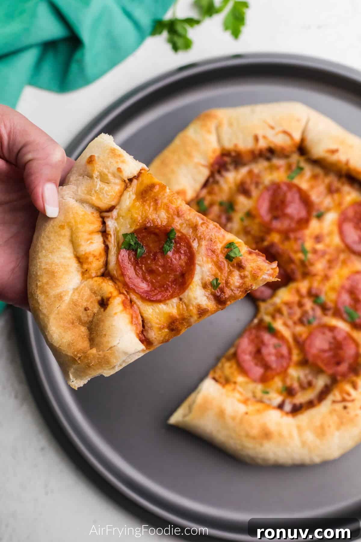 Slice of air fryer pizza being held. 