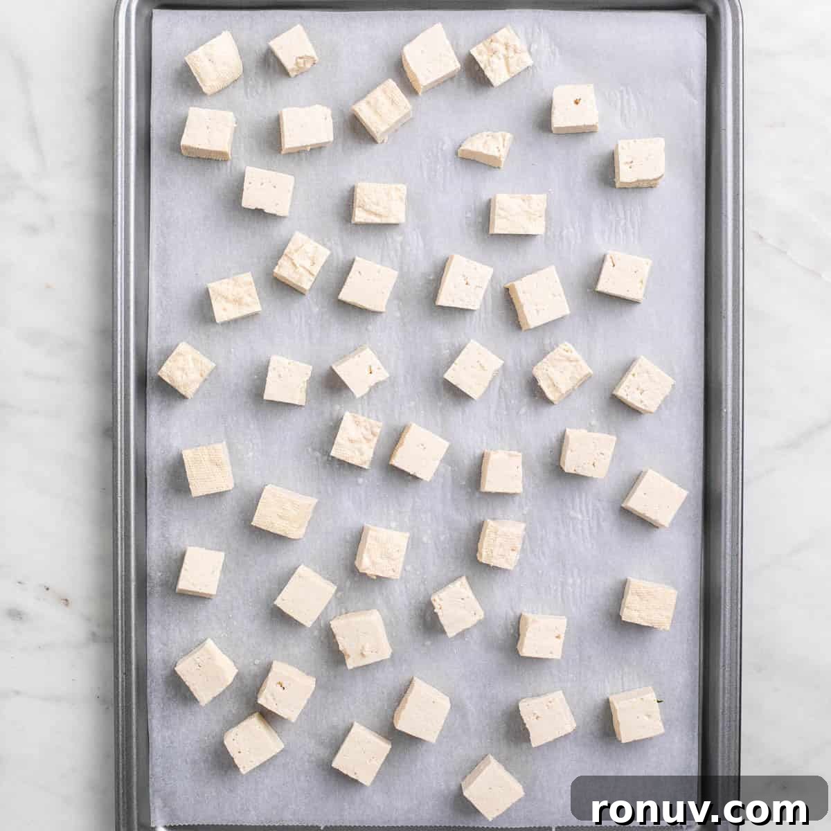 Freeze Tofu for Firmer Texture and Longer Storage 7 Tofu cubes on a lined baking sheet before freezing