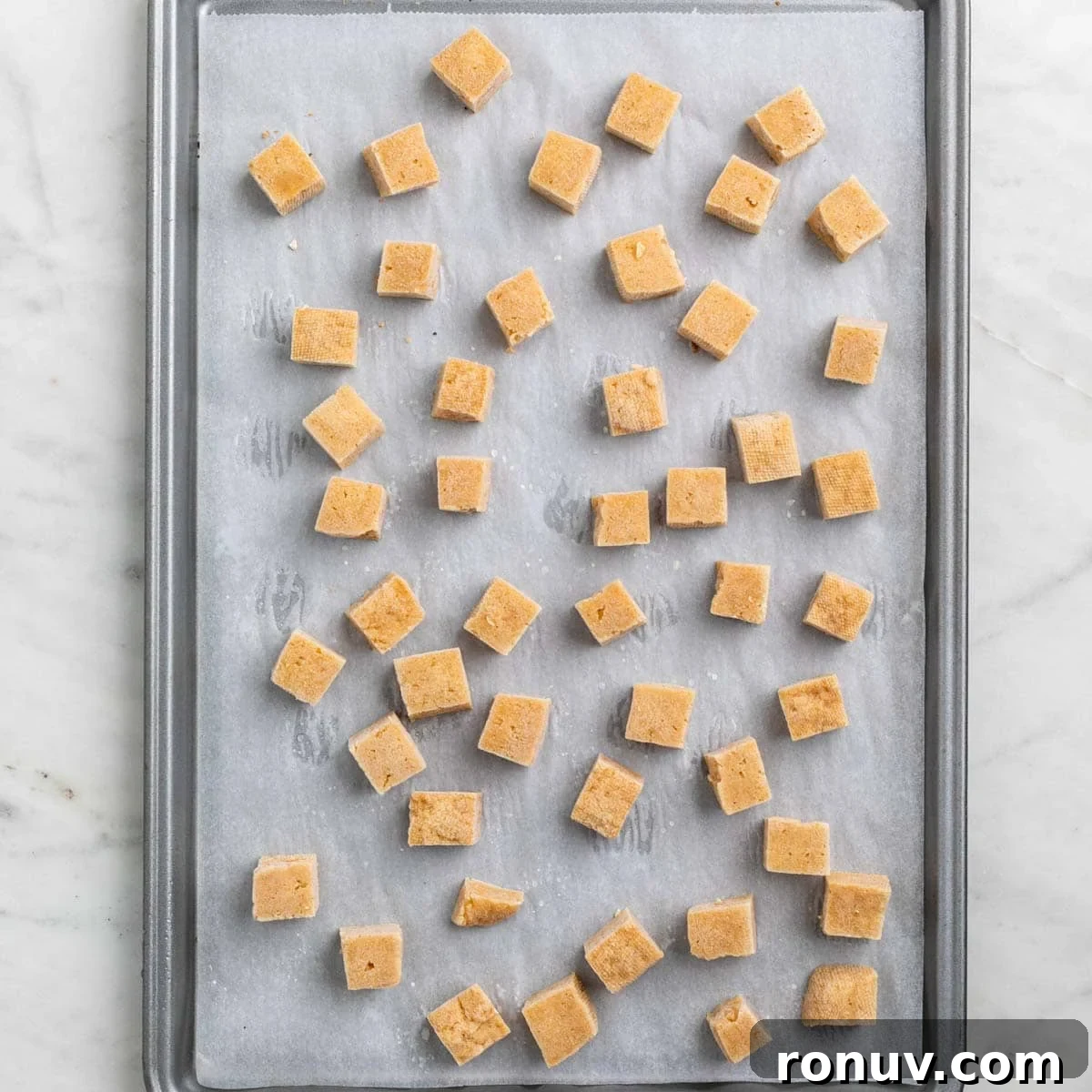 Freeze Tofu for Firmer Texture and Longer Storage 8 Frozen tofu cubes on a lined baking sheet