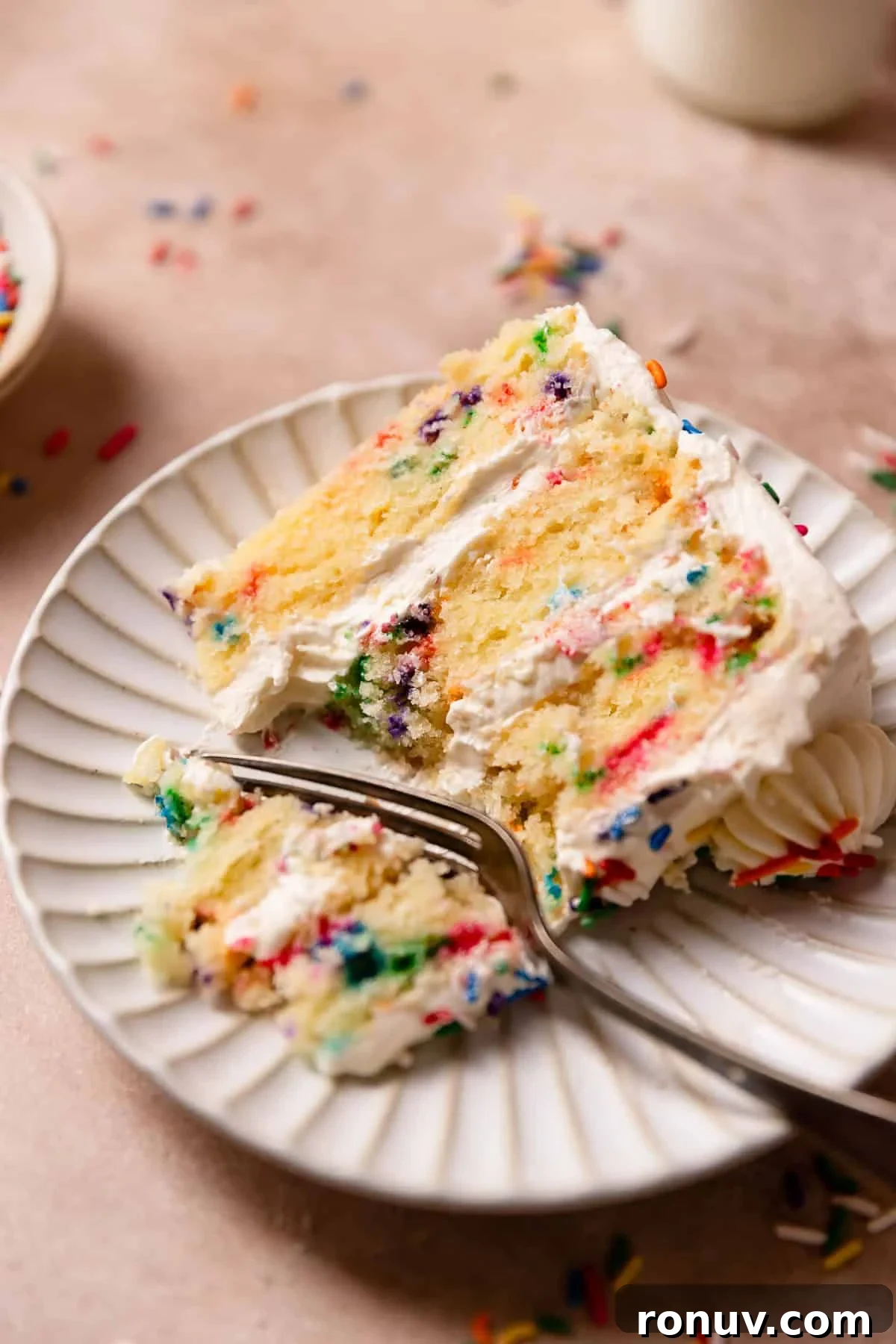 Homemade Funfetti Cake That Beats the Bakery 2 A slice of funfetti cake on a plate with a fork digging into a bite.