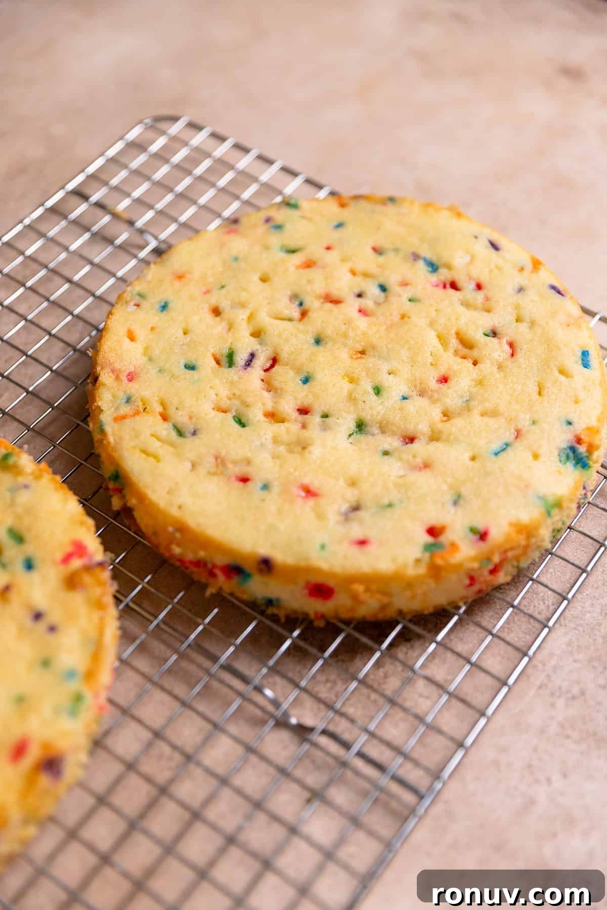Homemade Funfetti Cake That Beats the Bakery 6 Layers of funfetti cake cooling on a wire rack.